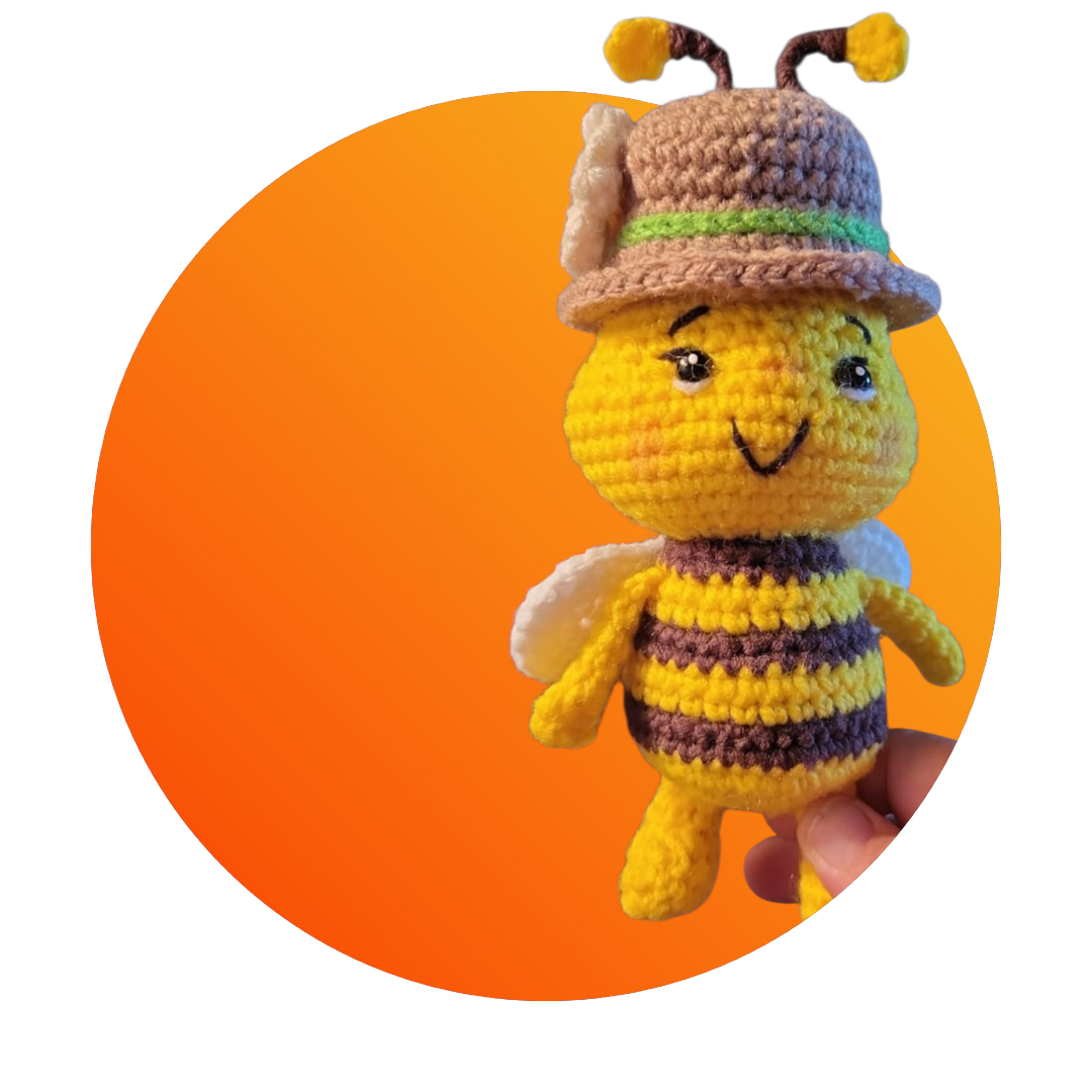 Crocheted bee toy with a hat on an orange background