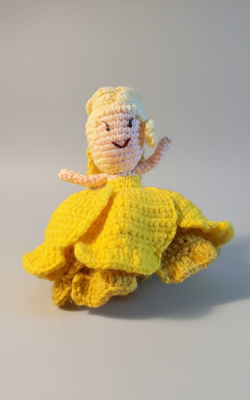Knitted doll in a yellow dress on a textured blue-green background